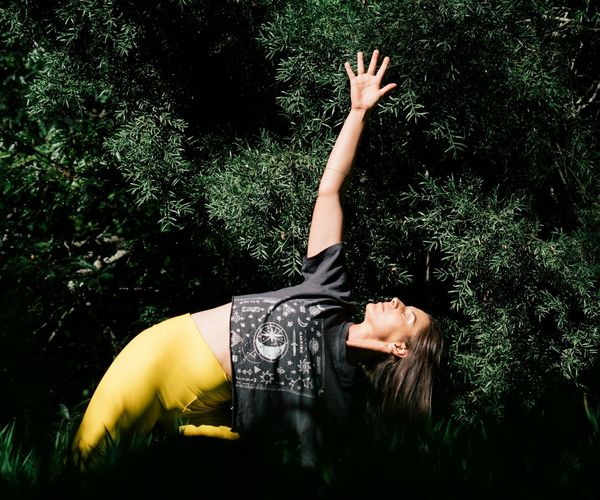 Woman in a peaceful yoga pose against a dark background with green light.